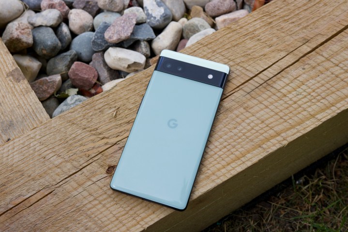 谷歌 Pixel 6a。我们看到手机的背面，它放在一块木头上。