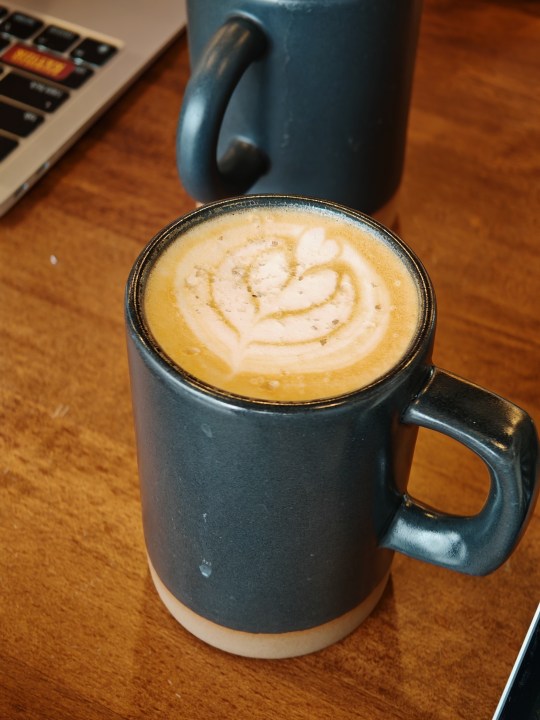 使用荣耀Magic 6 RSR拍摄的咖啡杯照片，上面画着心形。